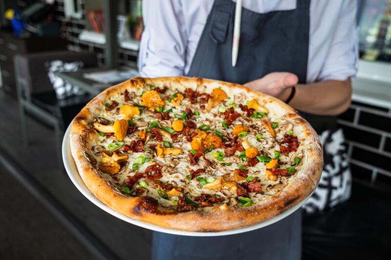 Chef holding a pizza with chanterelle mushrooms