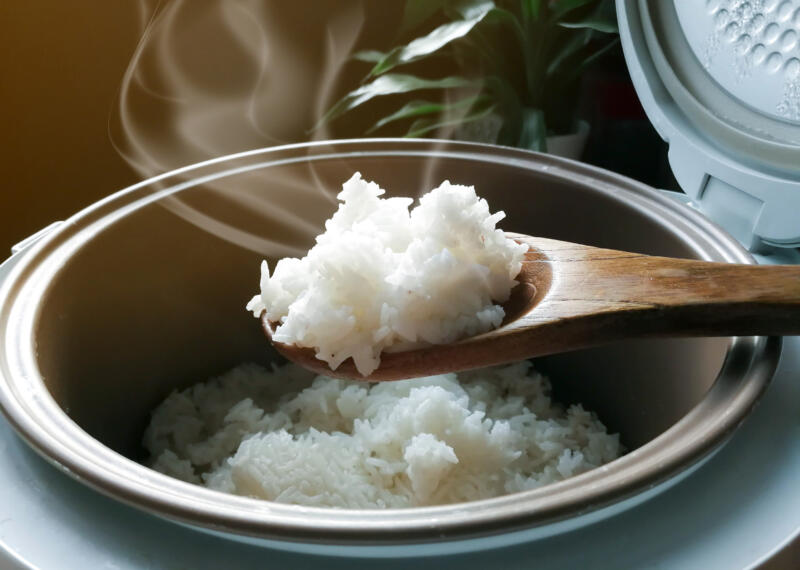 Jasmine rice cooking in electric rice cooker with steam. Soft Focus, rustic tone picture.