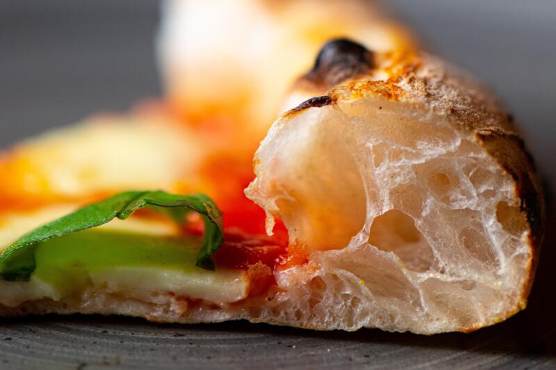 A crust of Margherita pizza on a blurred background