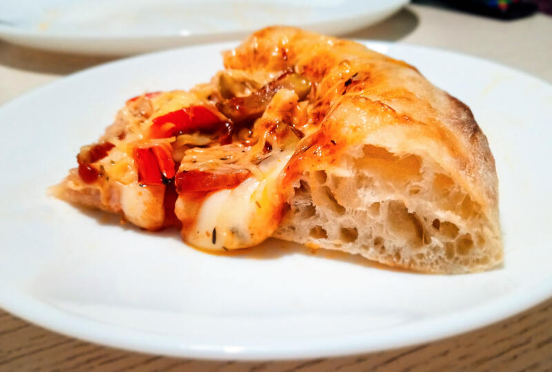 A slice of Neapolitan style pizza with a perfect cornicione on the plate