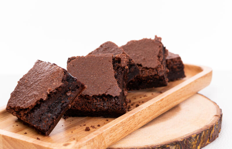 Unclean cut pieces of fudgy brownies on a wooden tray