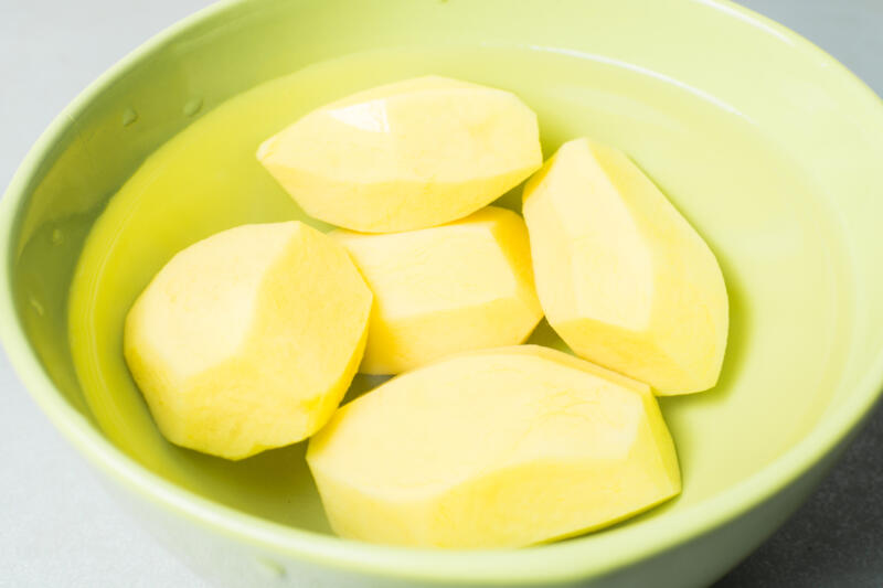 Peeled potatoes in a bowl of water