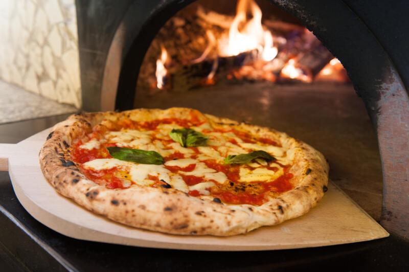 Taking out of the wooden oven really italian margherita pizza