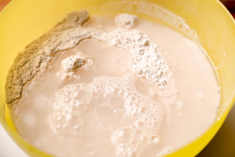 Mixing dry yeast, water, flour in a bowl for a pizza dough