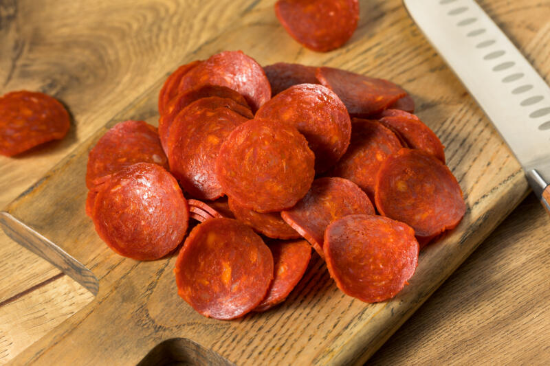 Uncured Italian pepperoni slices on a wooden board
