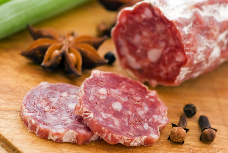 Salami pieces with some spices on a wooden board