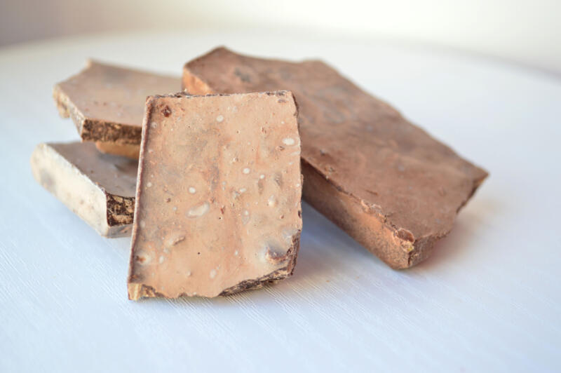 Grey spoiled chocolate pieces on a white background