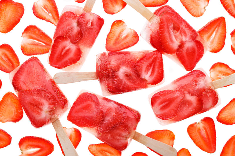 Homemade strawberry ice lollies on a white background, top view