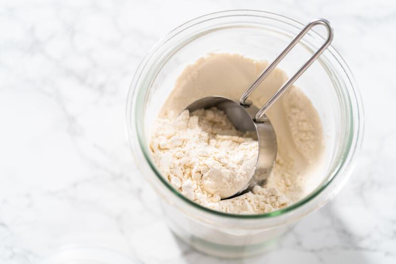 Measuring cup inside glass jar filled with all-purpose flour