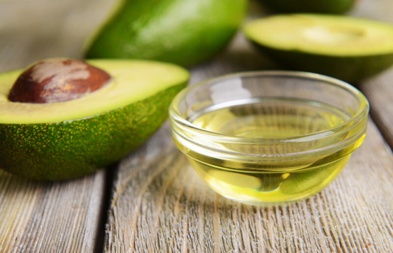 Cut fresh avocados and avocado oil in a bowl on a table