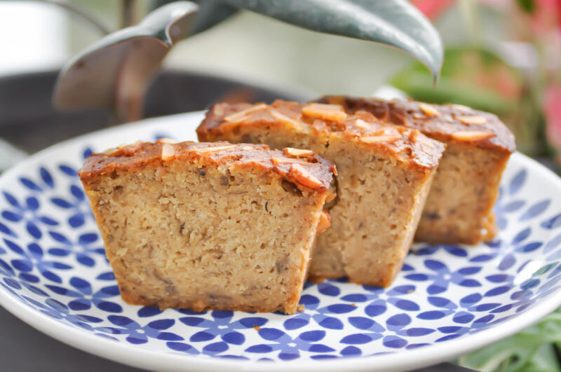 Slices of banana bread topped with almonds on a decorated plate