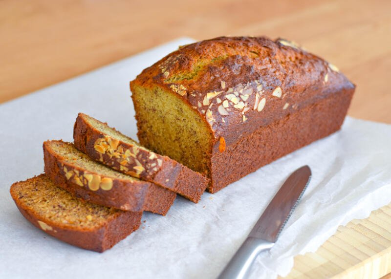 Sliced banana bread loaf with almonds on a cutting desk