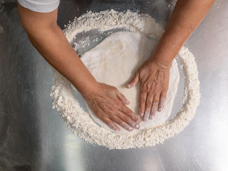 Stretching the pizza dough on a metal kitchen counter