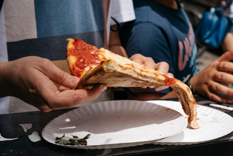 Folded slice of pizza in a hand close-up
