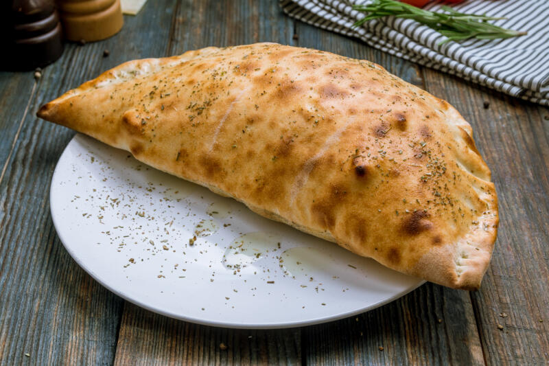 Closed pizza calzone on a plate on a table