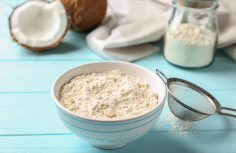 Bowl with coconut flour on wooden background