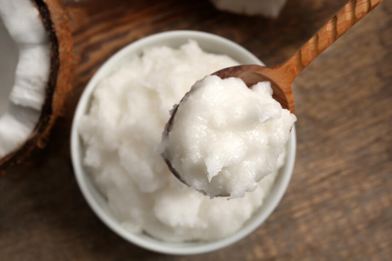 Wooden spoon with coconut oil over bowl on table