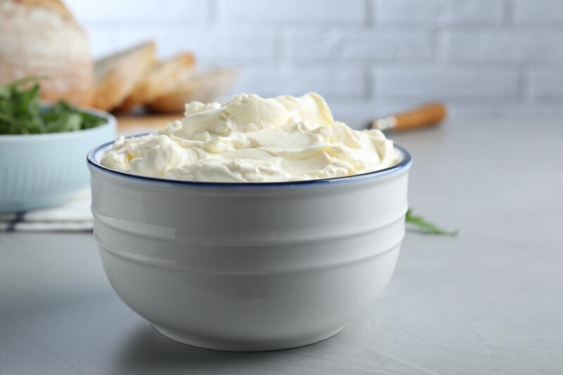 A bowl of cream cheese on a grey table