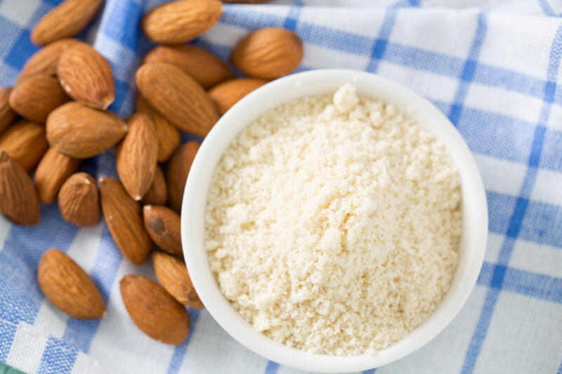 Almond flour in a bowl and whole almond on the table