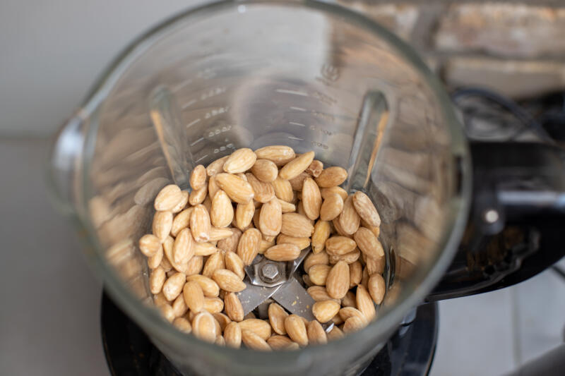 Whole almonds ready to be ground in a glass bowl of a chopper