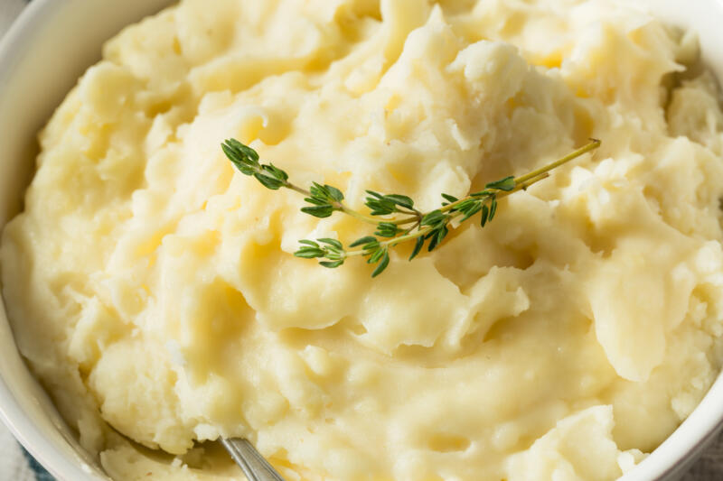 A bowl of homemade mashed potatoes decorated with thyme leaves