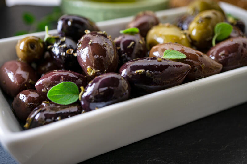 Marinated Kalamata olives in a white ceramic tray close-up