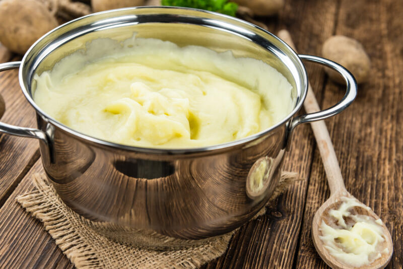 A large pot of a bit liquid mashed potatoes on a rustic wooden table