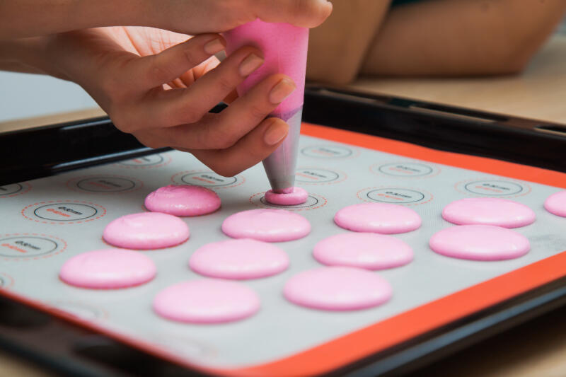 Female hands drop macaroons on baking mat