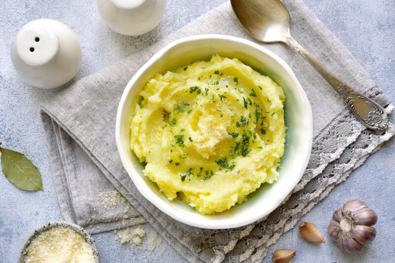 Potato mash with olive oil, Parmesan cheese and greens in a bowl