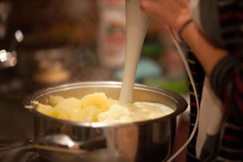 Close-up of mashing potatoes in a pot with a blender