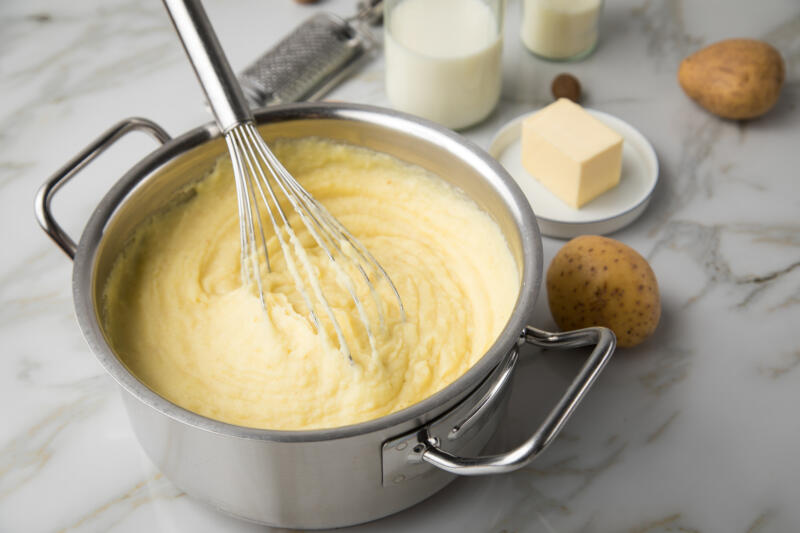 Cooking a pot of mashed potatoes with a help of a whisk