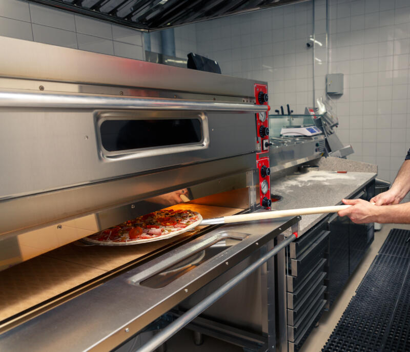 Putting a pizza in an electric oven in a pizzeria