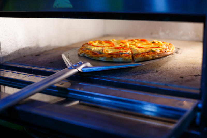 Taking a pizza from a pizza oven