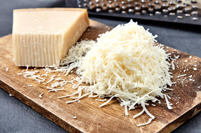 Grated Parmesan cheese and a grater on a kitchen counter