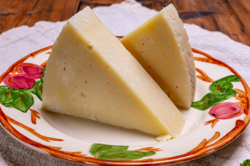 Two pieces of matured hard Italian cheese Pecorino Romano on a decorated plate