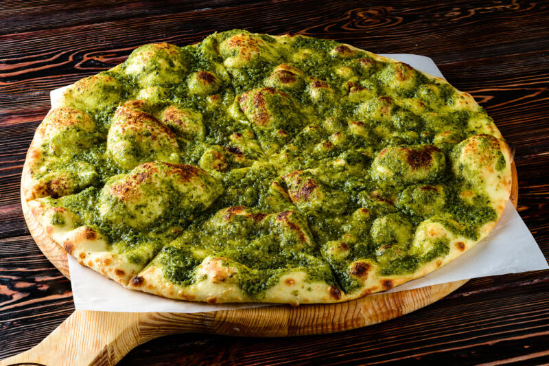 Vegetarian pizza with pesto sauce on it baked with beautiful bubbles