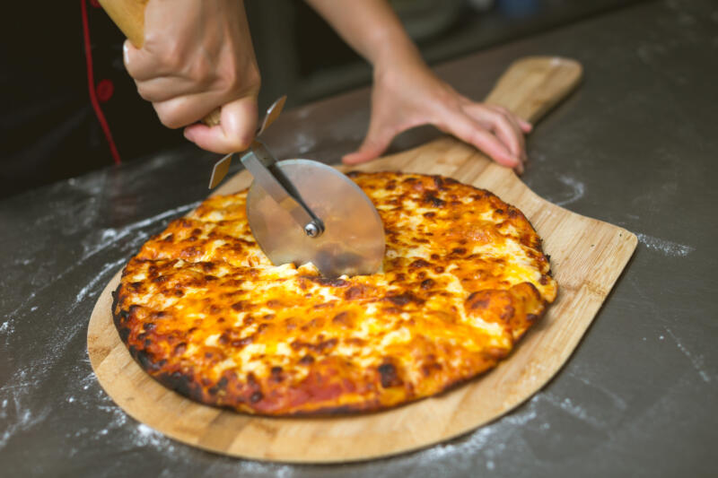 Chef cutting a pizza with a pizza wheal