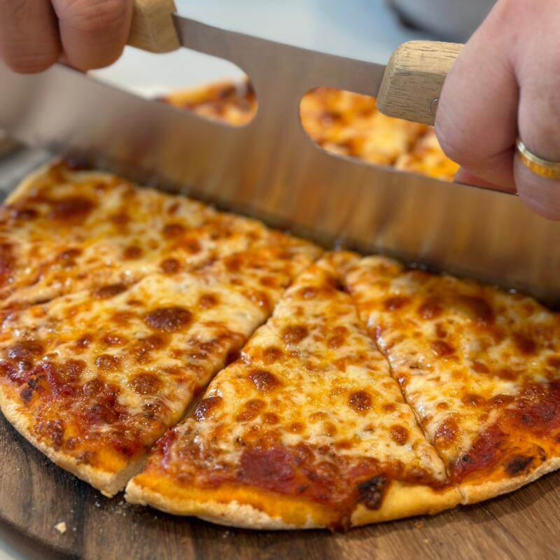 A man cutting a pizza into slices close-up