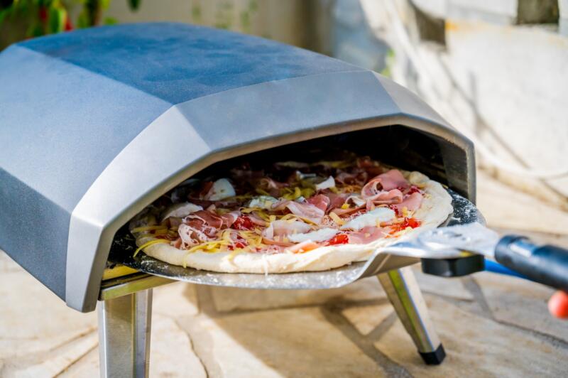 Putting a homemade pizza in portable high temperature gas oven