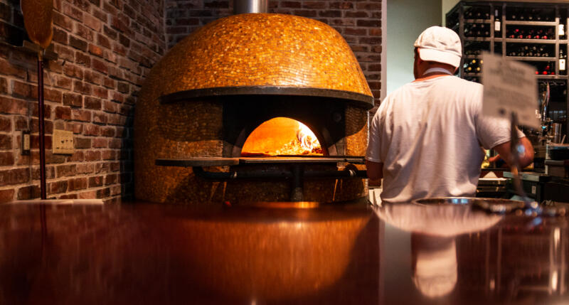 Chef is putting a pizza in a wood oven