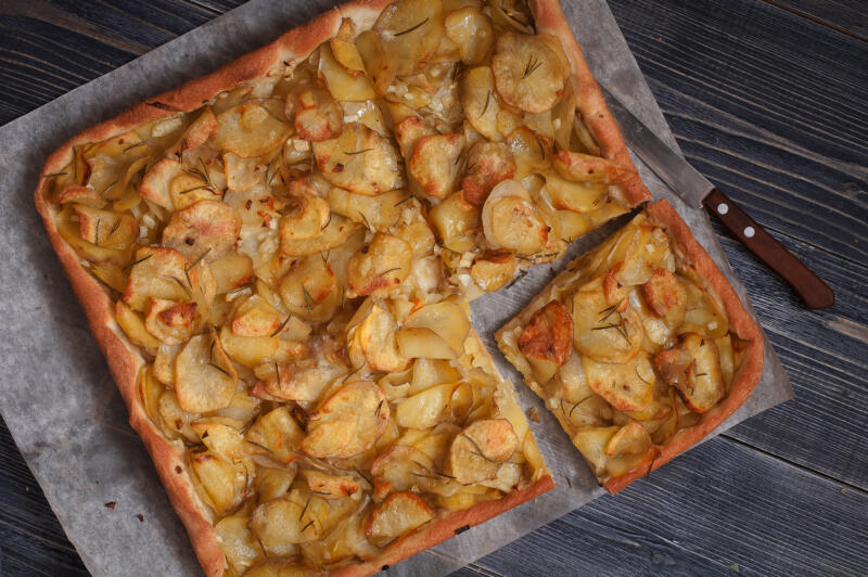 Vegetarian pizza with potatoes and without cheese on a parchment paper on the table