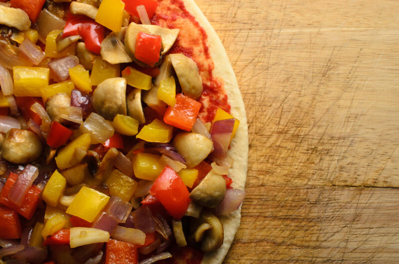 Overhead shot of pizza at the pre-baked stage. Topped with fried or sauteed mixed vegetables and no cheese