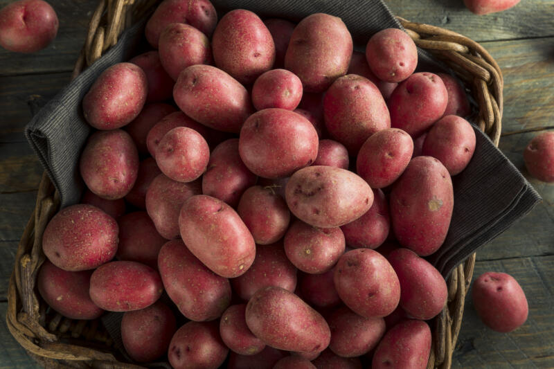 A pile of red waxy potatoes in a basket on a table