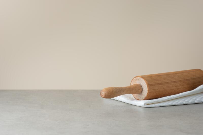 A white kitchen towel and a rolling pin on a kitchen counter