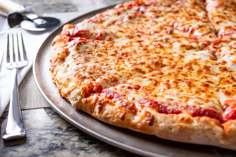 A view of a plain cheese pizza pie, in a restaurant or kitchen setting