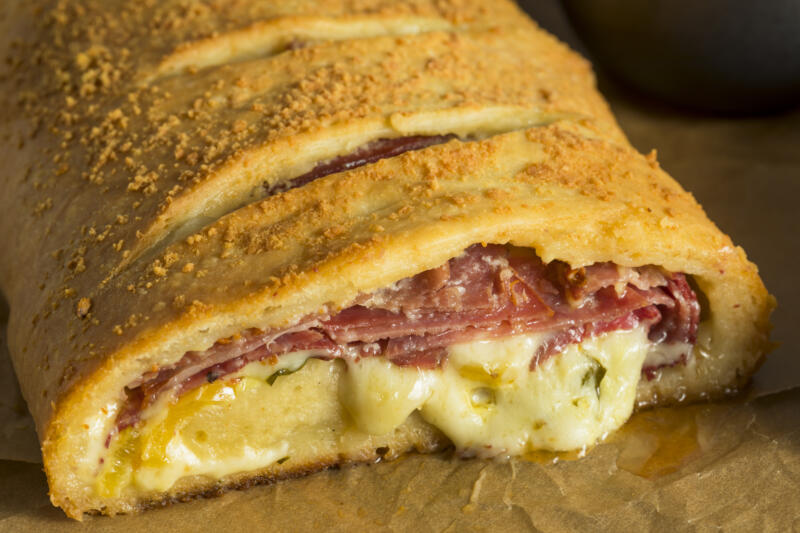 Close-up of a stromboli pizza with cheese and meat on a table