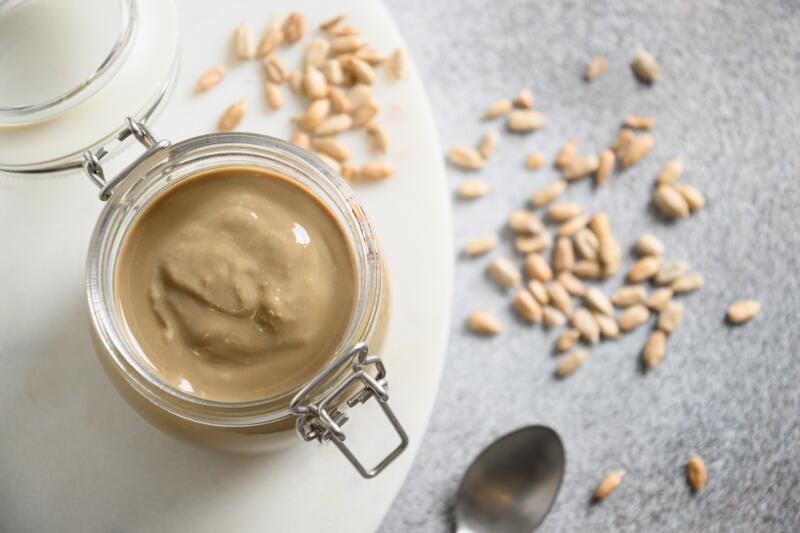 Sunflower seeds butter in a glass jar on a gray background