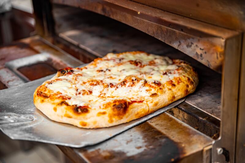 Taking out a thick-crust pizza from a commercial oven