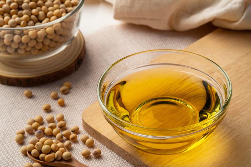 Vegetable oil extracted from the seeds of the soybean in a glass bowl on a wooden table