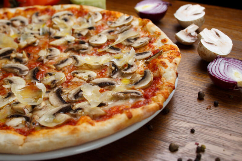 A pizza topped with white button mushrooms and onion on a table